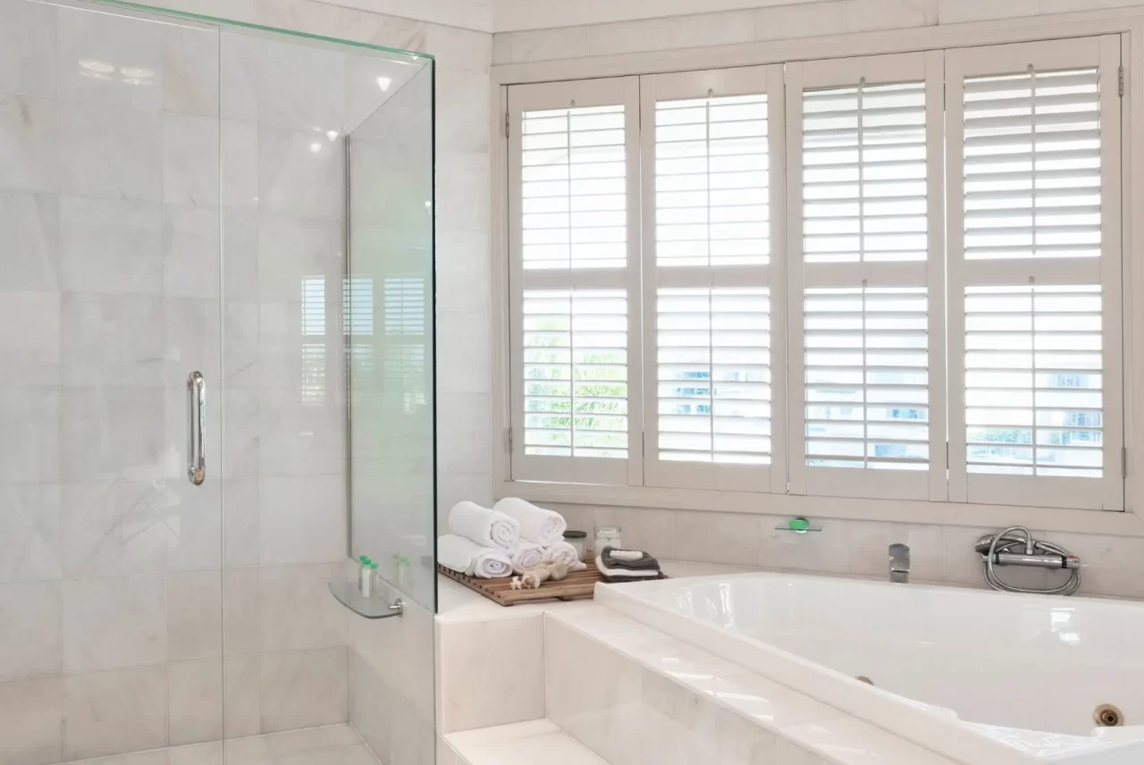 Four hinged shutter panels across a bathroom window, each with a mid-rail