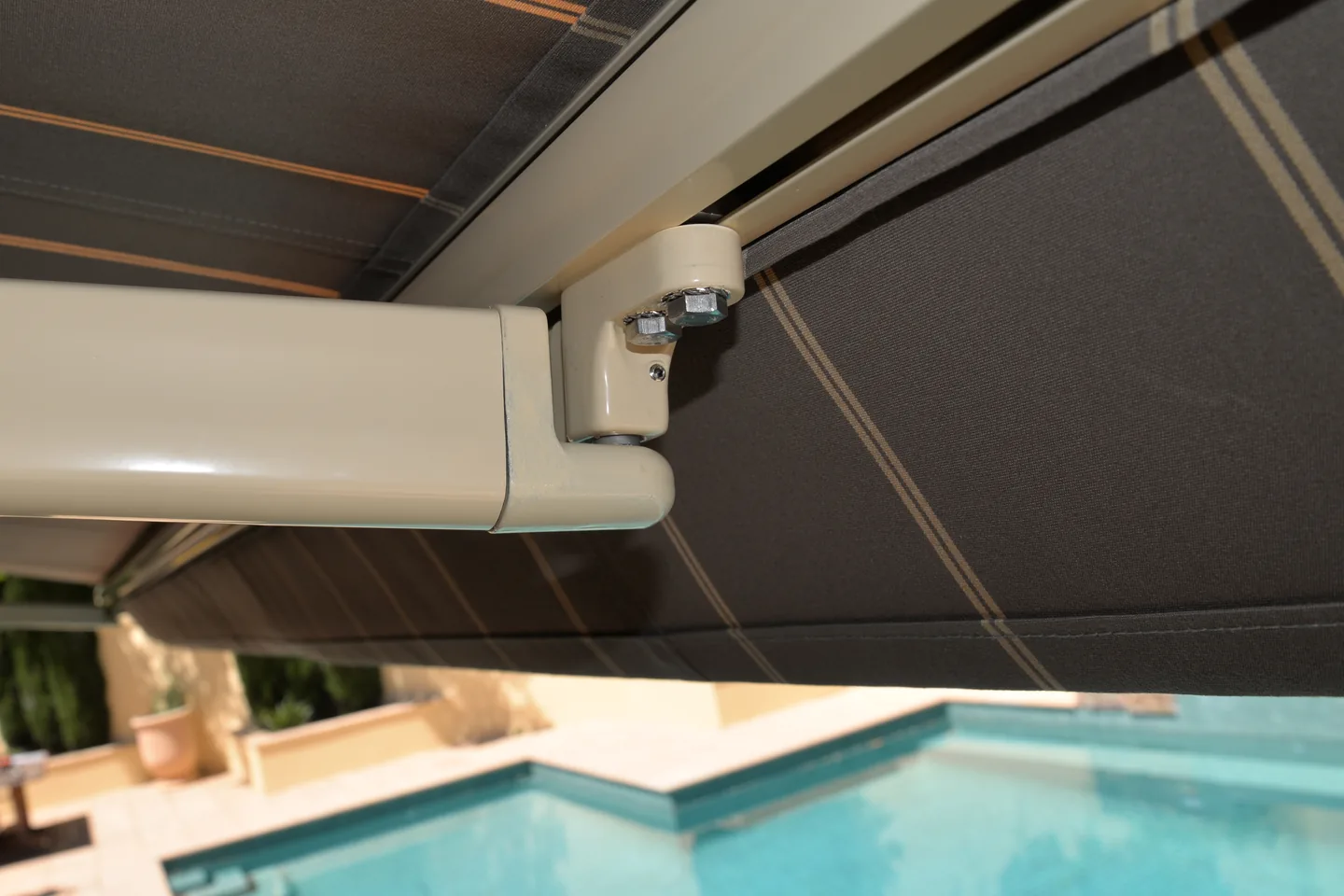 Folding arm and wall bracket under an extended awning above a pool