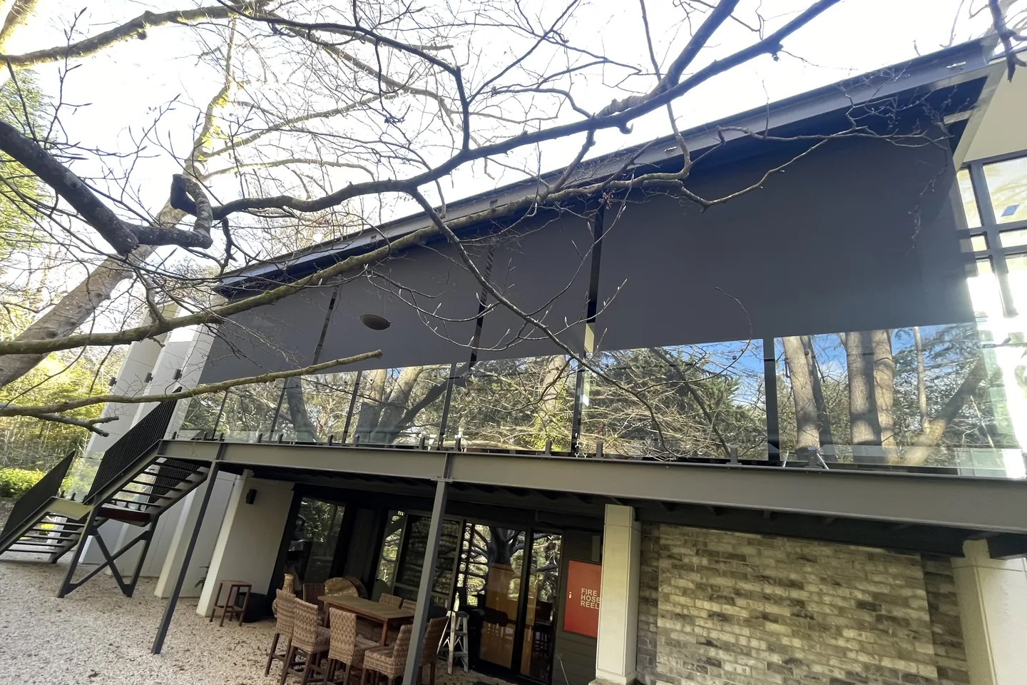 Wide straight drop awning lowered across an upper balcony of a stone home