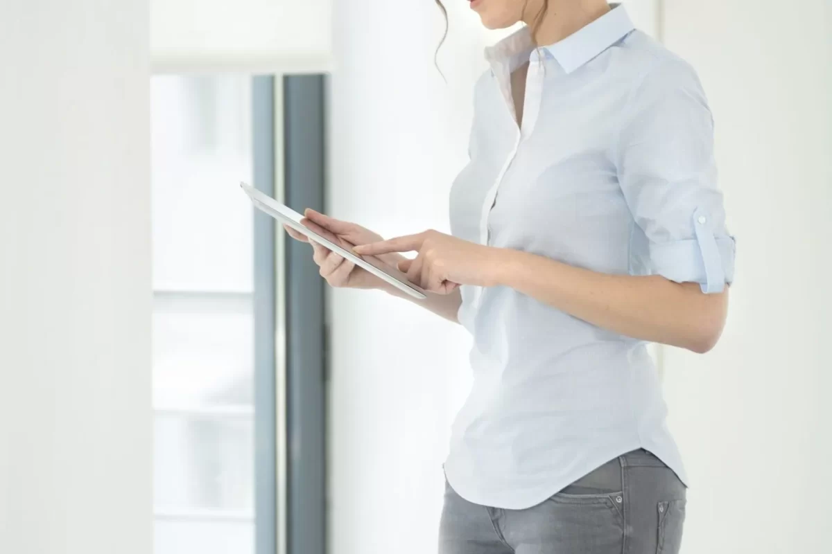 Woman using a tablet beside sheer curtains
