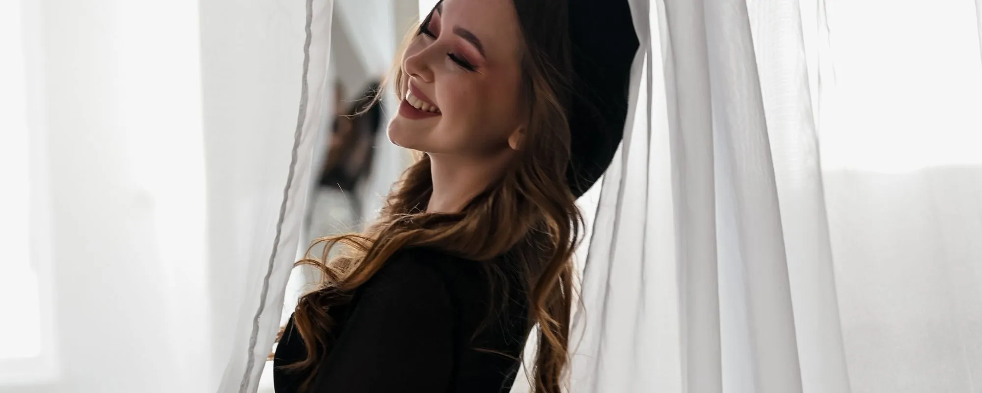 Woman smiling between sheer curtains