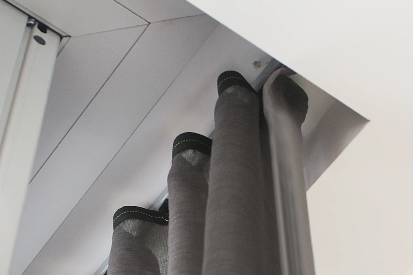 Looking up at the even S-fold waves of a charcoal curtain below a ceiling track