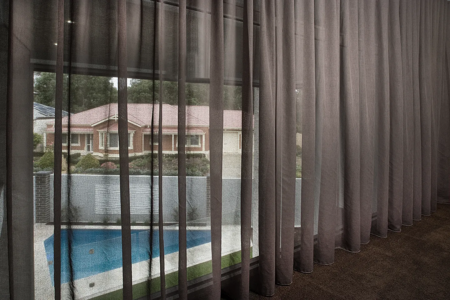 Charcoal sheer curtain filtering the view to a pool outside