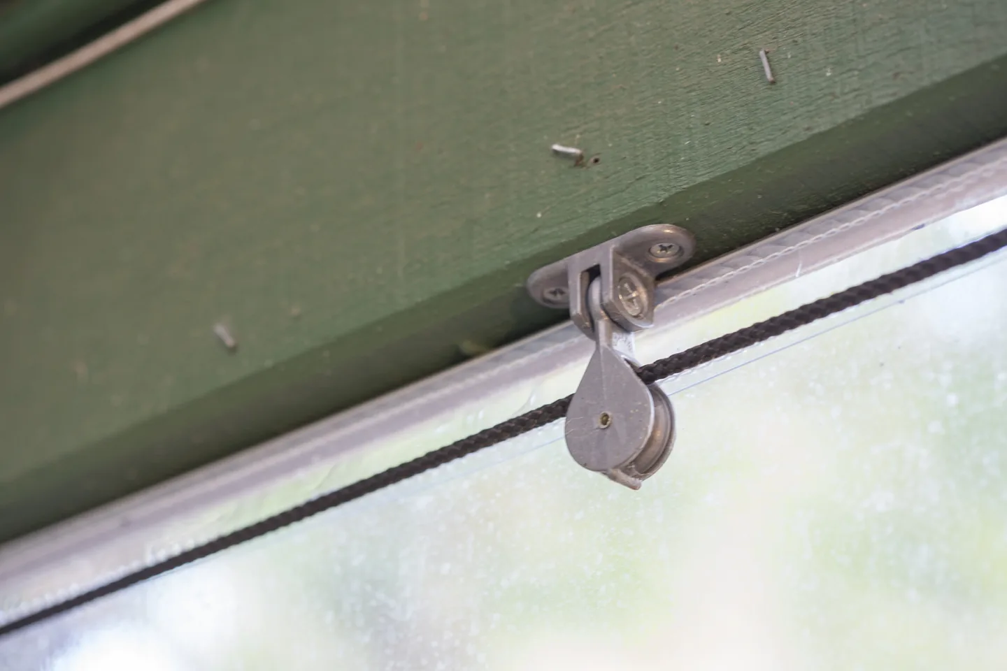 Pulley and cord fixed under the beam at the top of a clear cafe blind