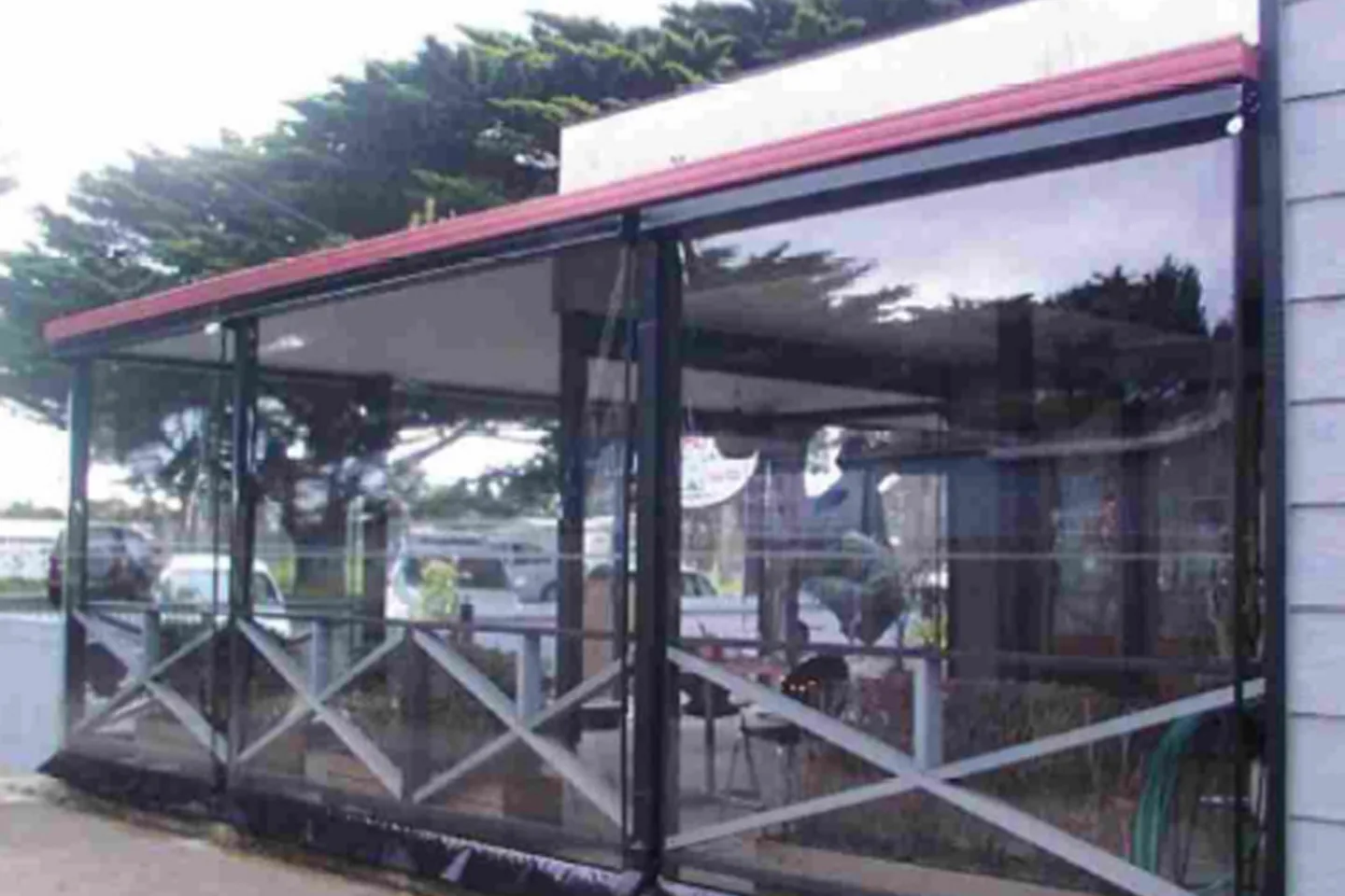 Verandah of a roadside cafe enclosed with clear PVC blinds above a timber balustrade