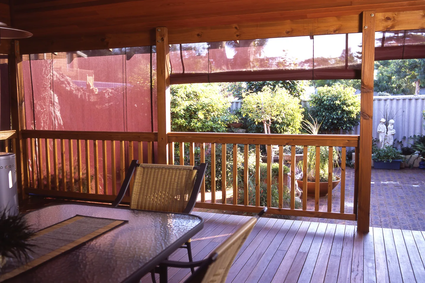 Covered timber deck with tinted outdoor blinds partly lowered above the balustrade
