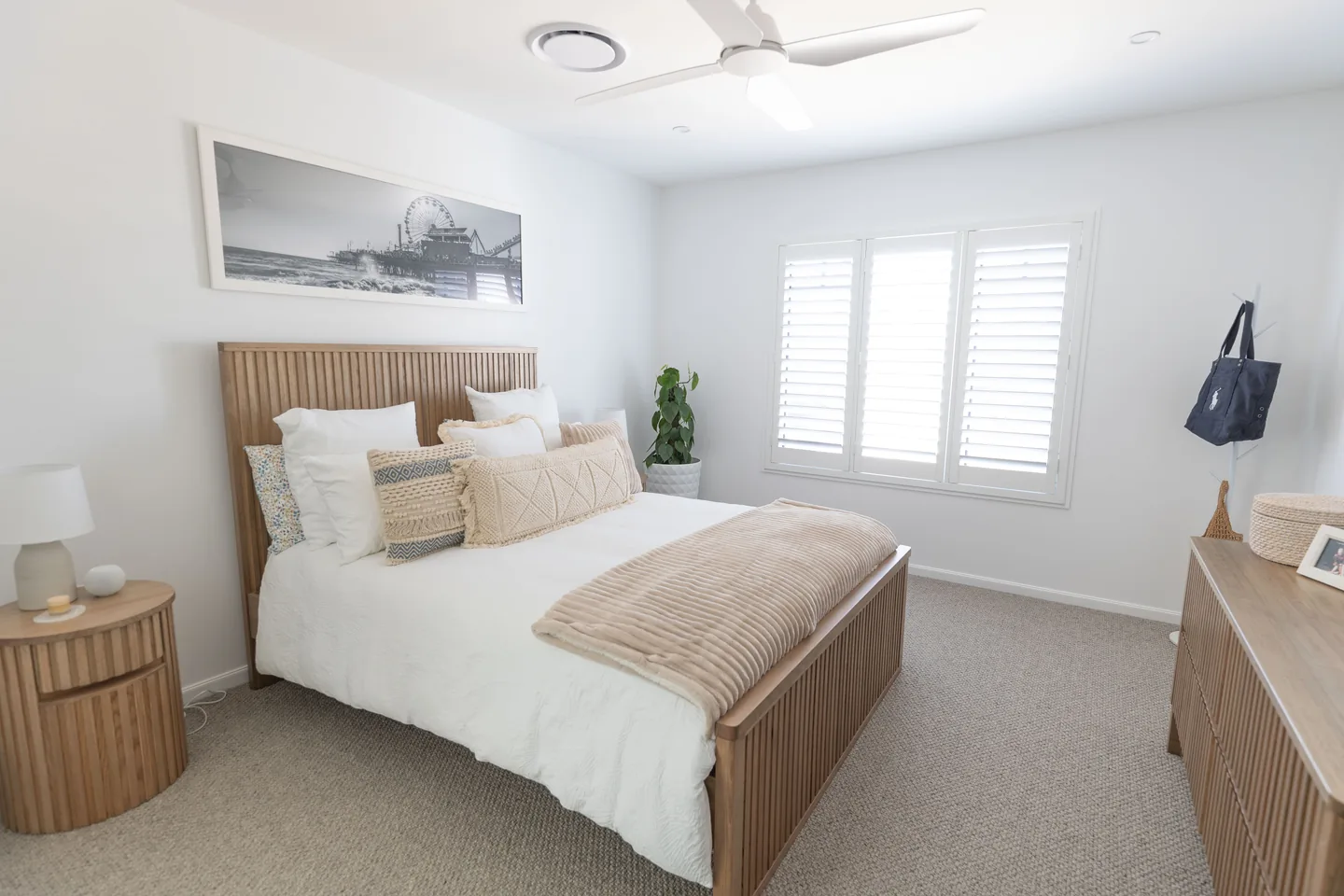 Bedroom with white plantation shutters on the windows, louvres open to daylight