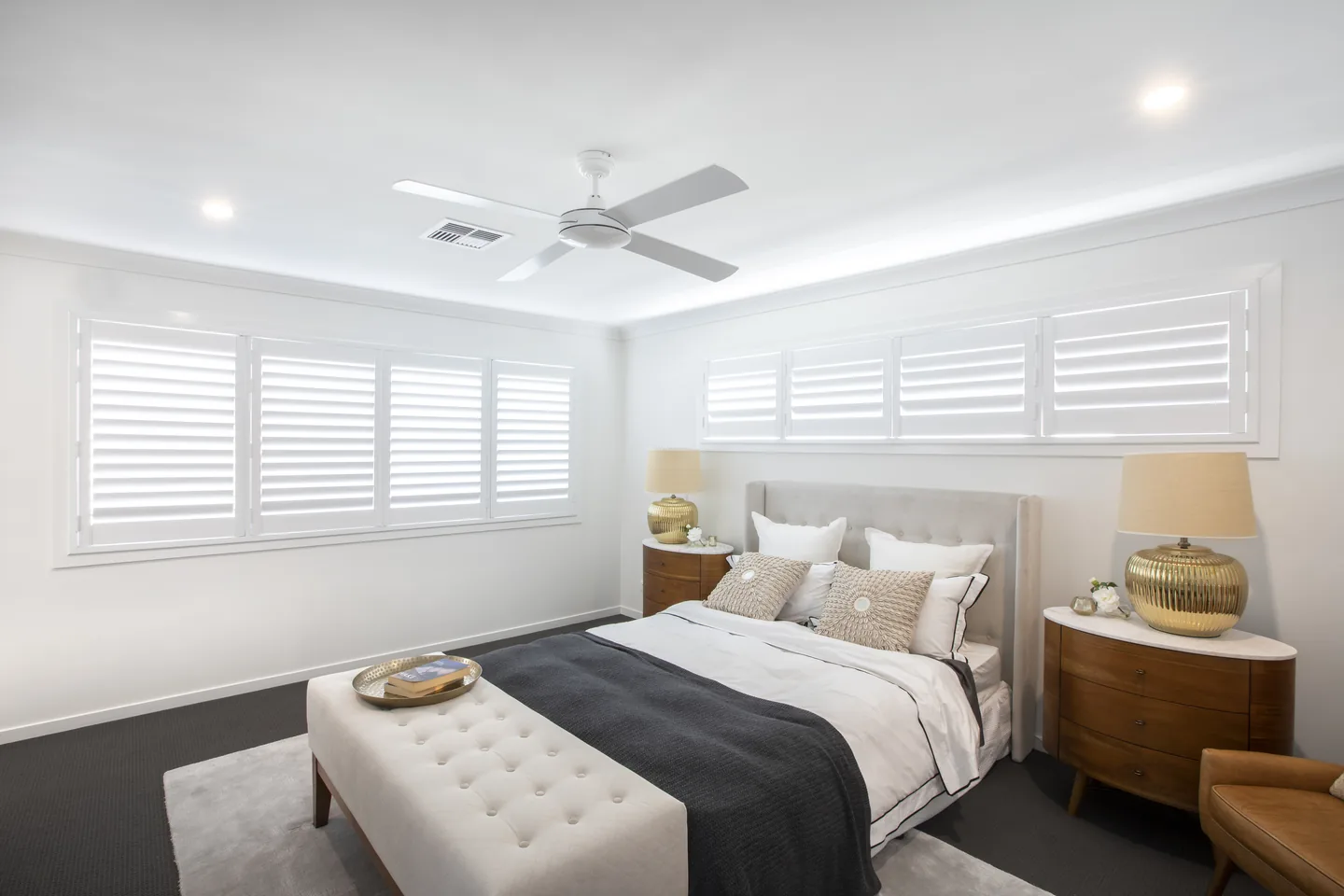 Bedroom with plantation shutters on high windows above the bed