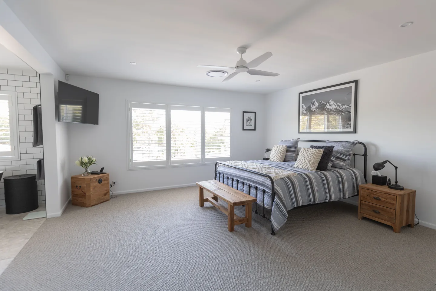 Main bedroom with white plantation shutters on a wide window